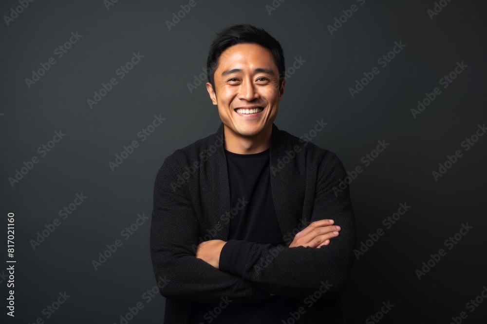 Portrait of a joyful asian man in his 30s with arms crossed over minimalist or empty room background Portrait of a joyful asian man in his 30s with arms crossed over minimalist or empty room background