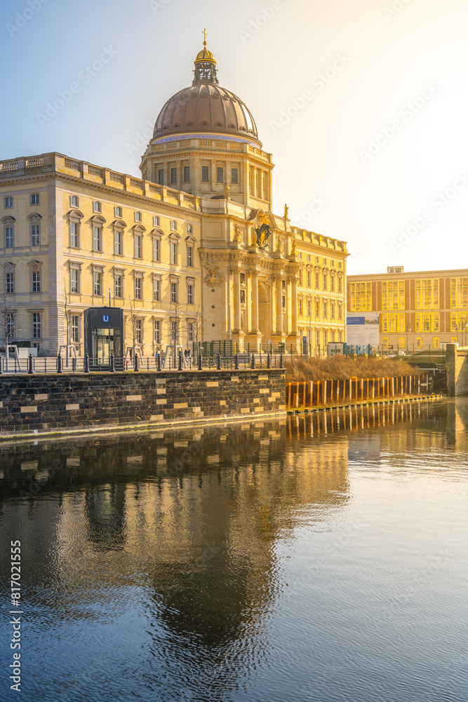 Fototapeta premium Golden morning sunlight bathes the Berlin Palace and Humboldt Forum, reflecting on the calm waters. Berlin, Germany