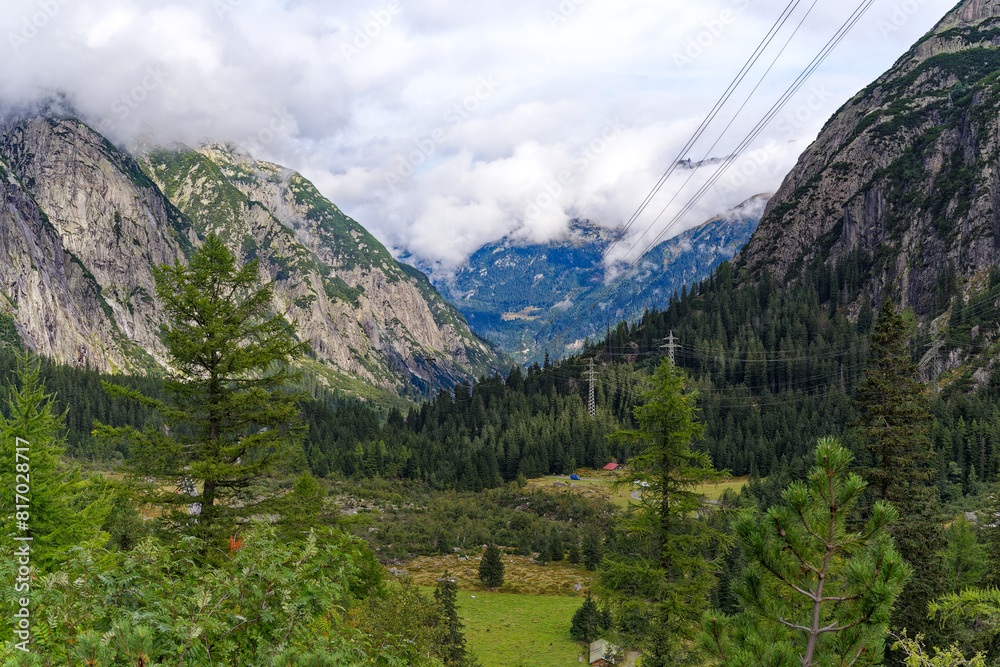 Obraz premium Alpine landscape in the Swiss Alps with fog and peak at mountain pass Grimsel on a cloudy late summer day. Photo taken September 19th, 2023, Grimsel, Canton Bern, Switzerland.