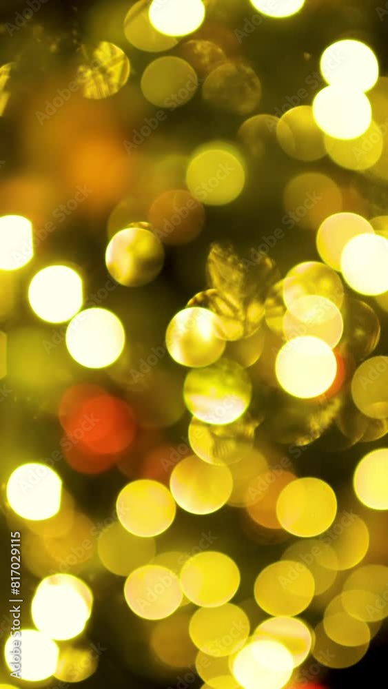 A bright garland with unfocused yellow bokeh balls for Christmas. New year holidays background with shiny lights. Vertical video. A bright garland with unfocused yellow bokeh balls for Christmas. New year holidays background with shiny lights. Vertical video.