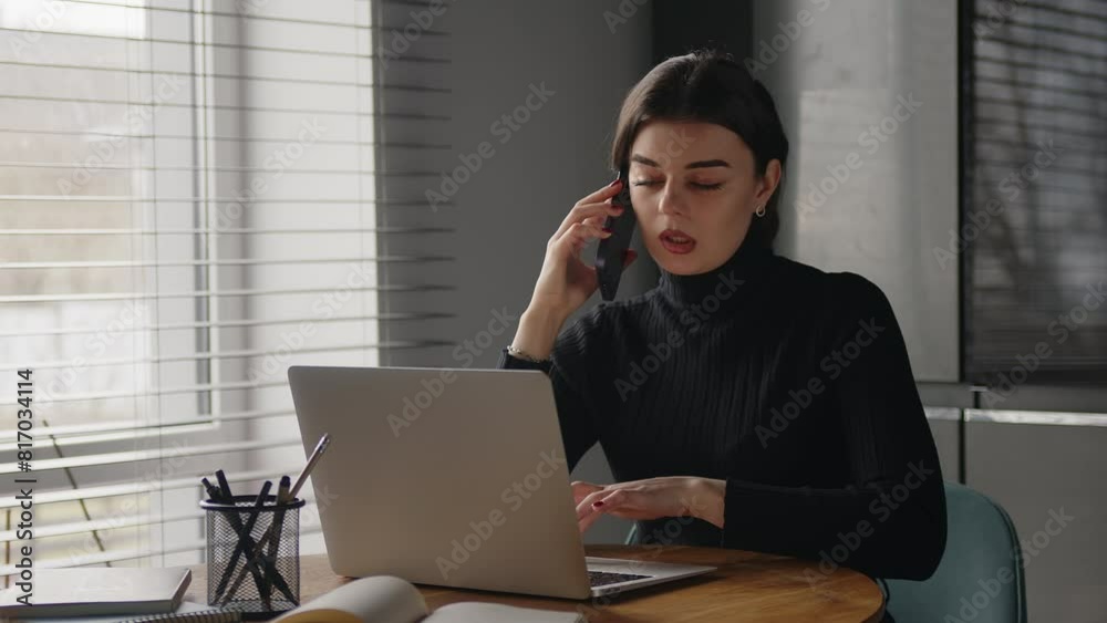 Portrait of beautiful young business woman talking with her mobile phone while consulting some invoices and documents in the kitchen at home.