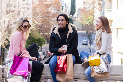 Multi-ethnic friends sitting on the street, talking and laughing