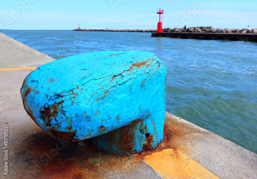 blue bollard that serves to securely moor ships to the port and a red lighthouse in the background photo