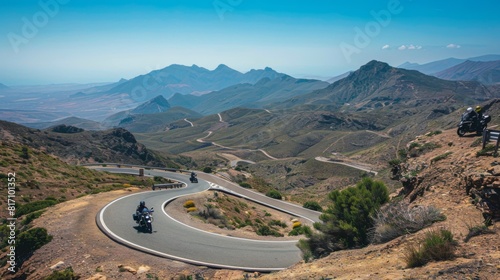 Motorcyclists navigating hairpin turns on a mountain pass road, with clear blue skies overhead.
