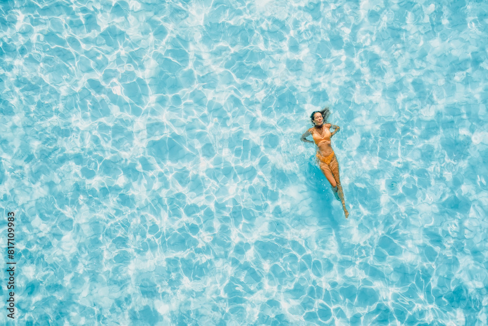 Woman swims and chilling in transparent blue sea. Drone view, top down view.