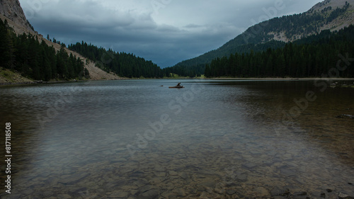 Lake with old log in the middle of the mountains photo