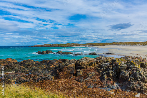 Balevullin Beach, Isle of Tiree, Scotland with rocks covered in dried seawee, marram grass, blue sky and beautiful beach.  Horizontal.  Space for copy