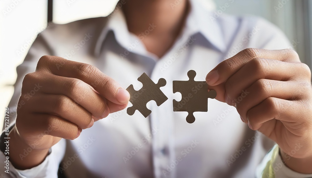 hands connecting two puzzle pieces together on office background hands connecting two puzzle pieces together on office background
