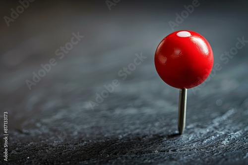 A red pin on a black surface with a black background