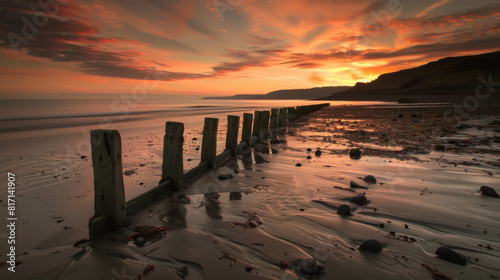 A beach with a wooden fence and a sunset in the background