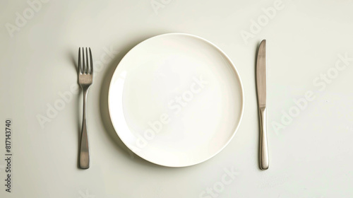 A silver fork and knife are on a white plate. The plate is empty, and the silverware is clean. Concept of simplicity and minimalism, with the focus on the basic elements of a meal