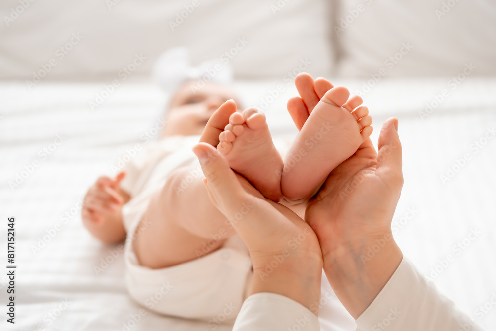 mom's hands hold the legs of a small child on a white background mom's hands hold the legs of a small child on a white background