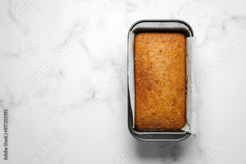 Banana bread loaf in a baking tin on marble background