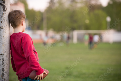 Little soccer player standing in the goalposts defending the the line and ready to throw a football. Cute kid boy standing as goalkeeper on a sportsfield on a sunny day. Sport activities for children photo