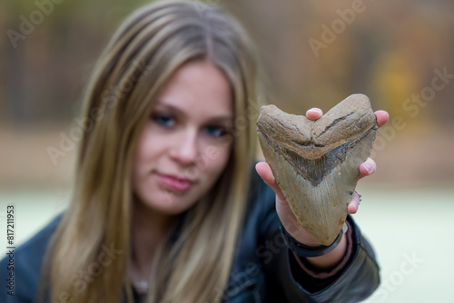 Young girl holding a large Megalodon shark tooth photo