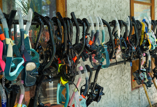 Group of rental snorkels, goggle and diving gears hanging to dry at a shop or service for tourist on the beach.