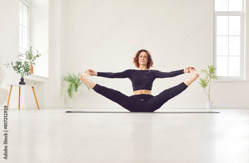 Yogi sporty attractive woman practicing yoga, doing stretching warm up exercise in sitting pose, working out, wearing black sportswear, home sport or modern studio fitness for healthy lifestyle Yogi sporty attractive woman practicing yoga, doing stretching warm up exercise in sitting pose, working out, wearing black sportswear, home sport or modern studio fitness for healthy lifestyle