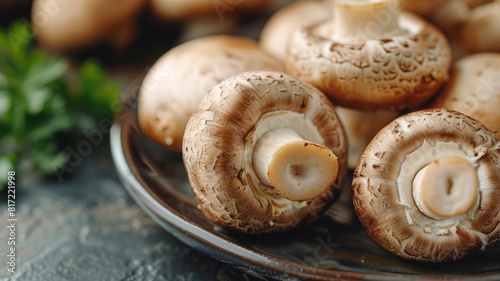 Close-up of fresh brown mushrooms on a plate with parsley in the background.
