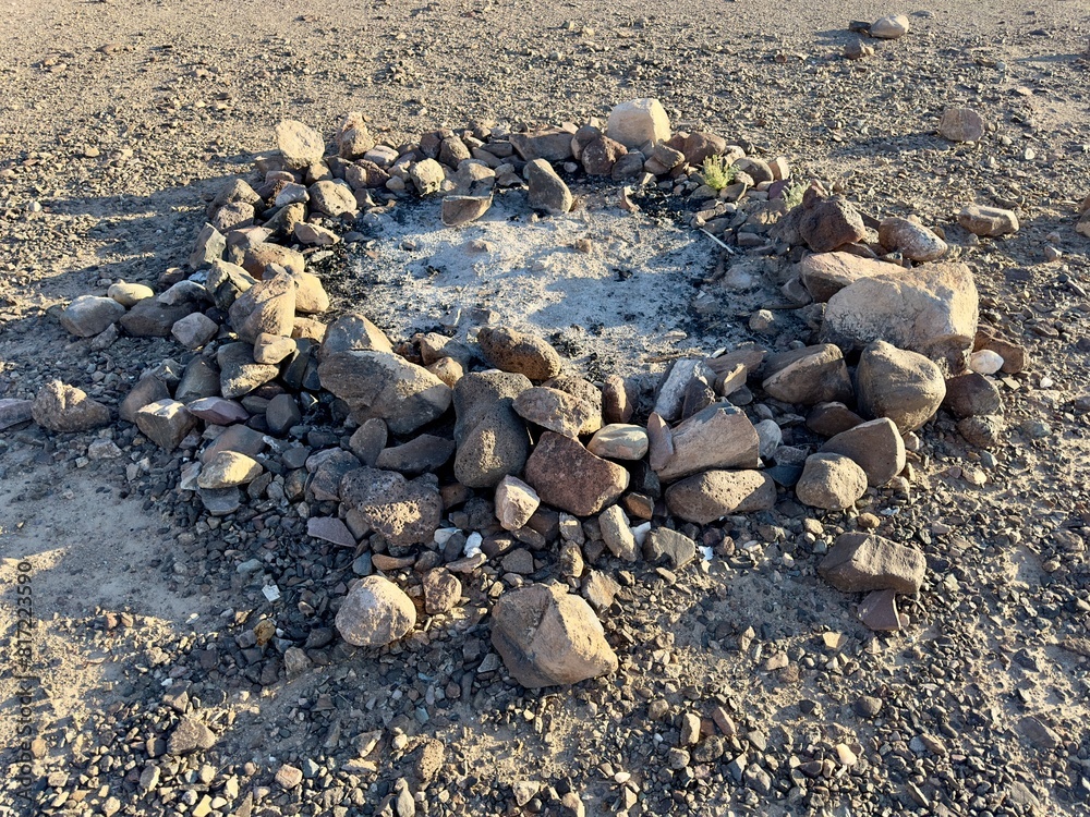 A desert campground firepit glows warmly, surrounded by sand, cacti, and tents, creating a cozy oasis under the starry sky. A desert campground firepit glows warmly, surrounded by sand, cacti, and tents, creating a cozy oasis under the starry sky.