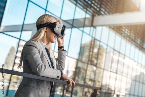 Young businesswoman wearing virtual reality headset simulator outside modern office building. Young woman in VR headset looking away at the objects in virtual reality.