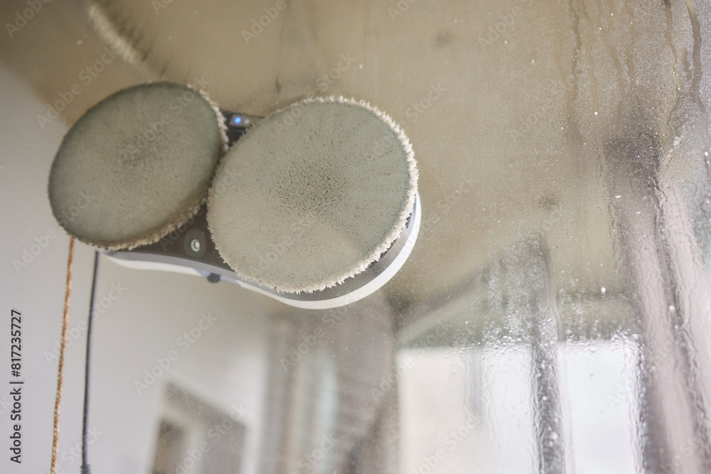 A robotic white Automotive tire is cleaning a glass window