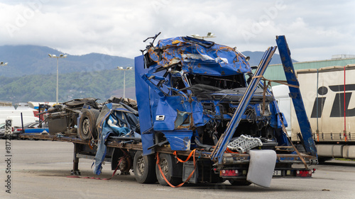 фотографія Dented blue truck cab and a semi-trailer on a tow platform in the parking lot after a serious accident