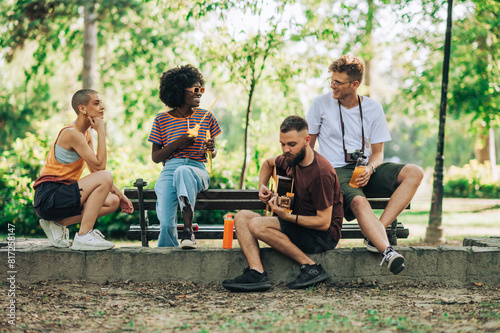 фотографія Group of multicultural hippie friends having jam session in park.