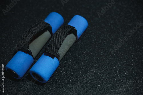 Top view of blue - black dumbbells on a black background. Workout equipment for training at home top view. Fitness, workout items, healthy lifestyle concept. photo