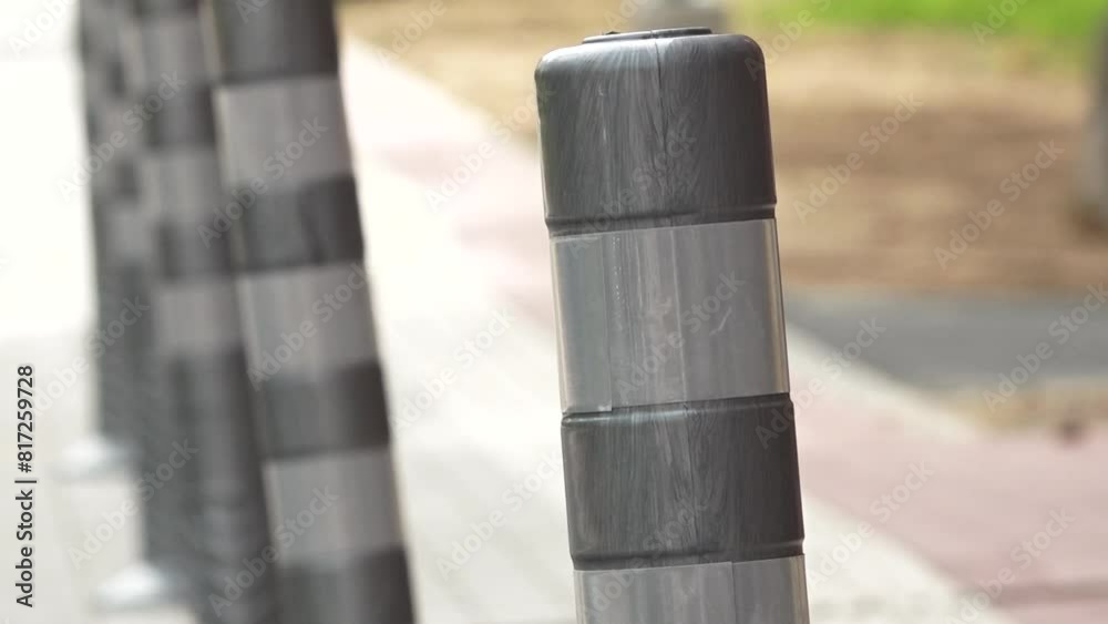 Close-up of gray plastic bollards lined up on a sidewalk, creating a pattern and providing safety and separation from the street. Close-up of gray plastic bollards lined up on a sidewalk, creating a pattern and providing safety and separation from the street.