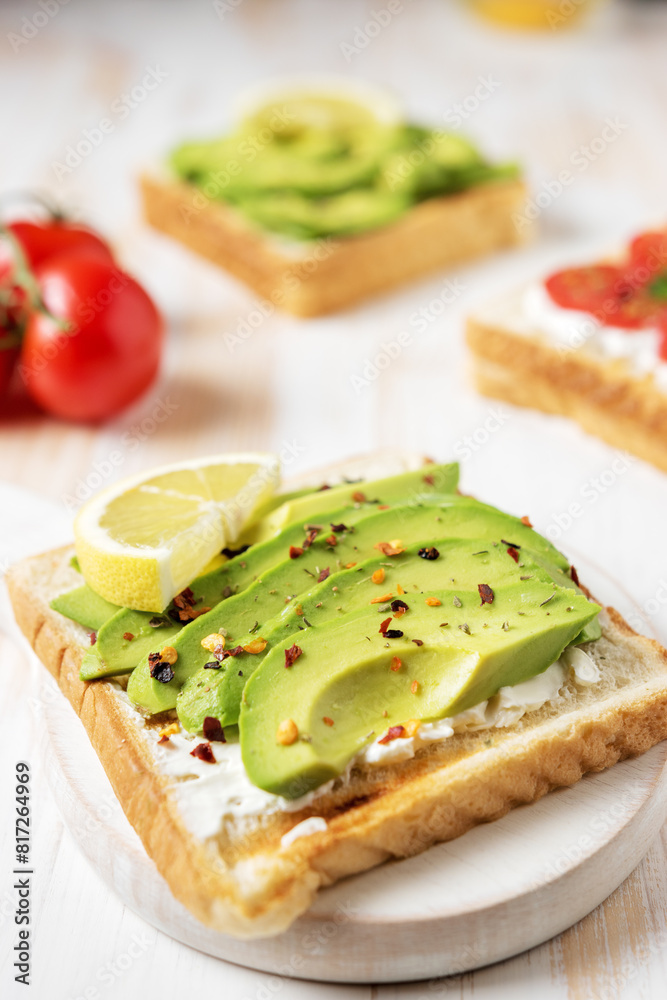 Sliced avocado on toast bread with spices on white wooden background. Food concept.