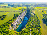 The breathtaking aerial view captures the lush green surroundings and turquoise waters of the abandoned Velka Amerika limestone quarry on a sunny summer day. Morina, near Prague, Czechia