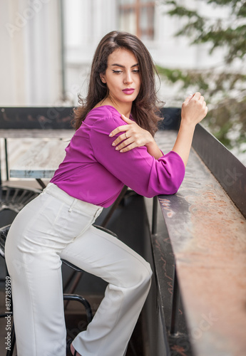 Obraz na płótnie Beautiful young brunette woman in a purple blouse and white pants posing outdoor. Portrait of a beautiful young brunette woman with long hair posing fashion w salonie