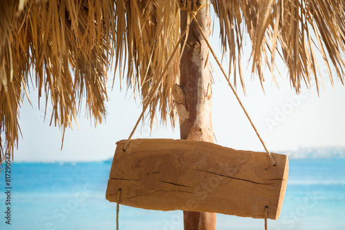 Wooden signboard hanging on a rope on the beach
