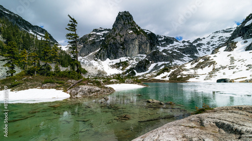 Mountain lake with green water and glacier on cloudy day