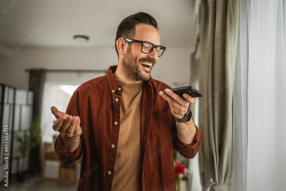 Adult man stand and record voice message on mobile phone at home Adult man stand and record voice message on mobile phone at home