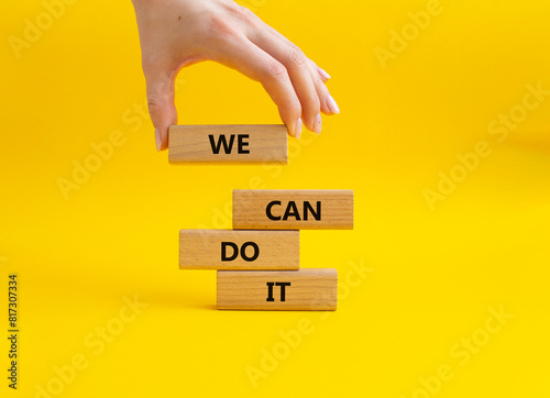 We can do it symbol. Concept words We can do it on wooden blocks. Beautiful yellow background. Businessman hand. Business and We can do it concept. Copy space.