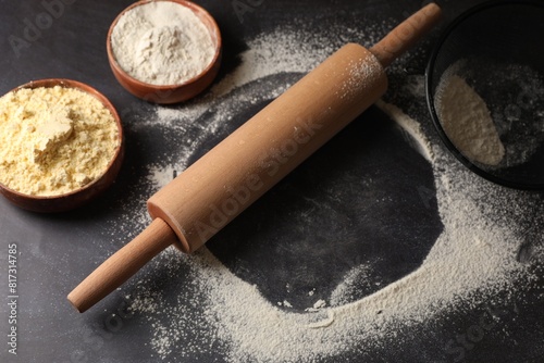 Scattered flour, rolling pin and sieve on black table photo