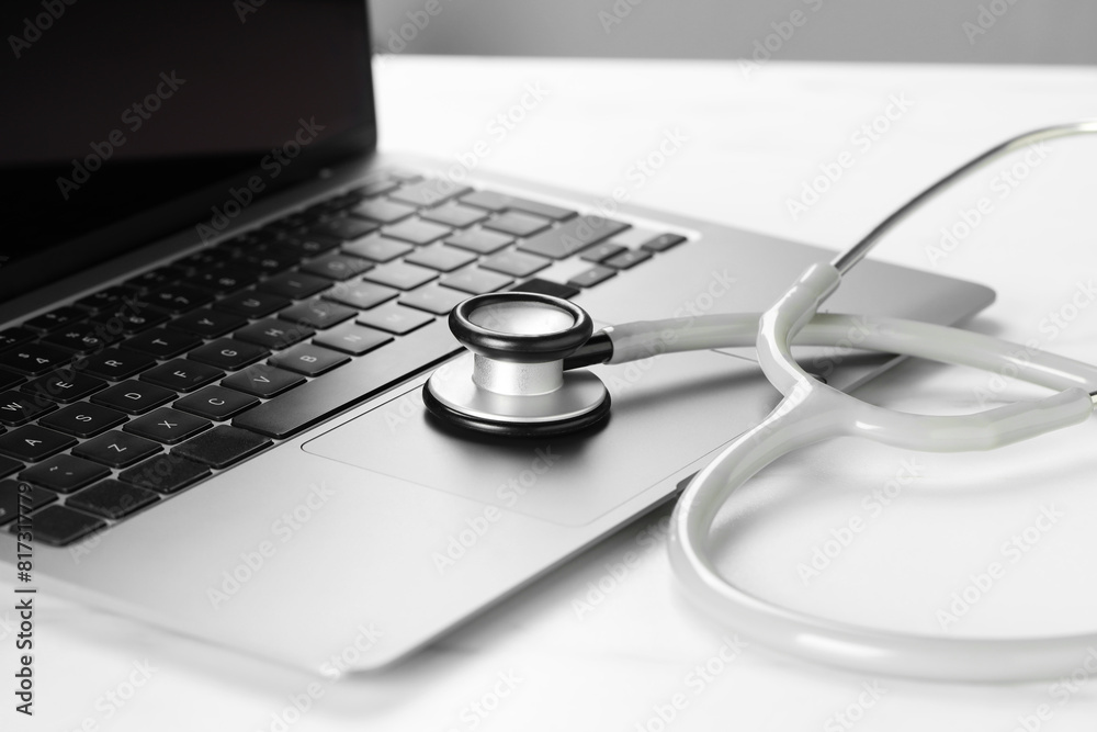 Modern laptop and stethoscope on white table, closeup Modern laptop and stethoscope on white table, closeup