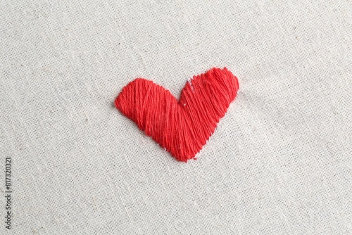 Embroidered red heart on light cloth  top view