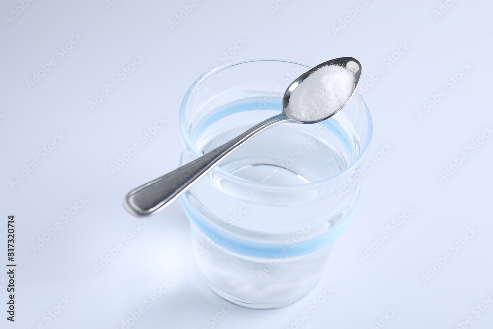 Glass of water and spoon with baking soda on white background Glass of water and spoon with baking soda on white background