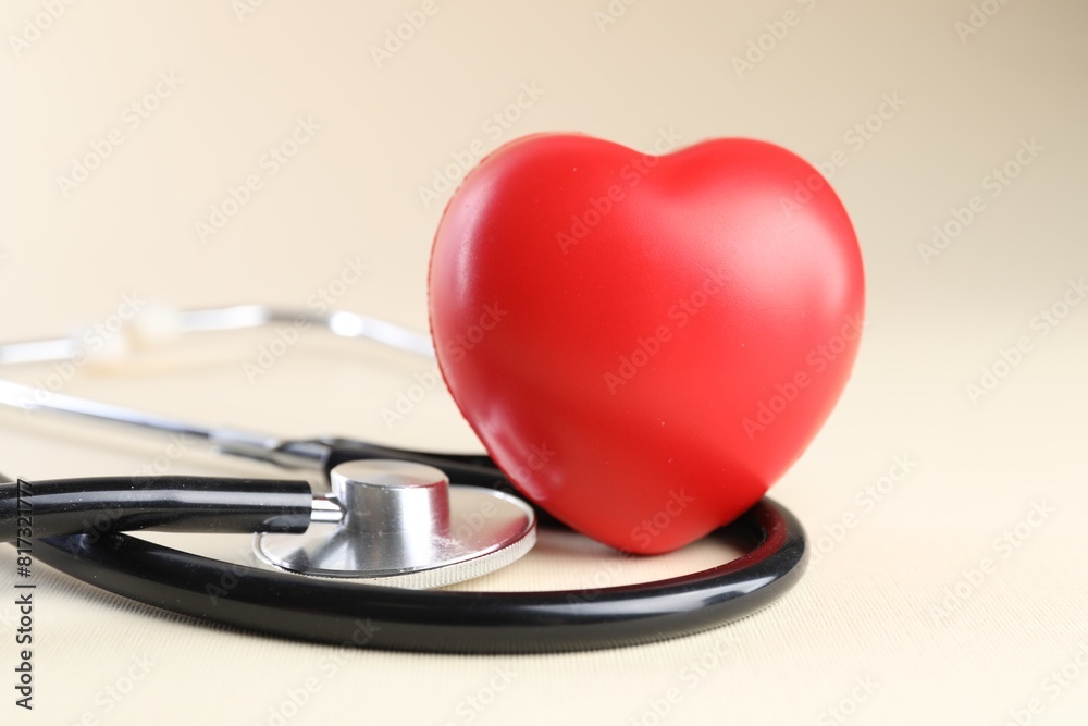 Stethoscope and red heart on beige background, closeup Stethoscope and red heart on beige background, closeup