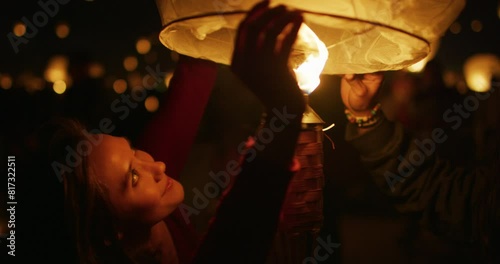 Happy woman lighting up Chinese lantern - steady cam shot photo