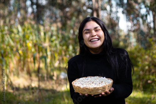 La cosecha del esfuerzo,una campesina bonita orgullosa muestra el fruto de su trabajo en la tierra, sosteniendo en su mano una canasta rebosante de maíz,alegre mujer,trabajo,estilo de vida photo