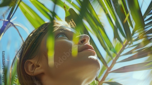 A woman in a close up portrait relishes the beauty of nature as she gazes up at palm tree leaves capturing a moment of awe and wonder while exploring different corners of the globe photo