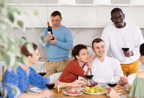 Happy companions congregated around a festive table  participating in animated discussions and enjoying the delights of red wine