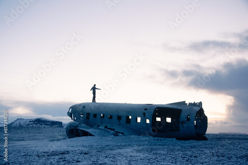 Person standing on an abandoned airplane in snowy Iceland photo