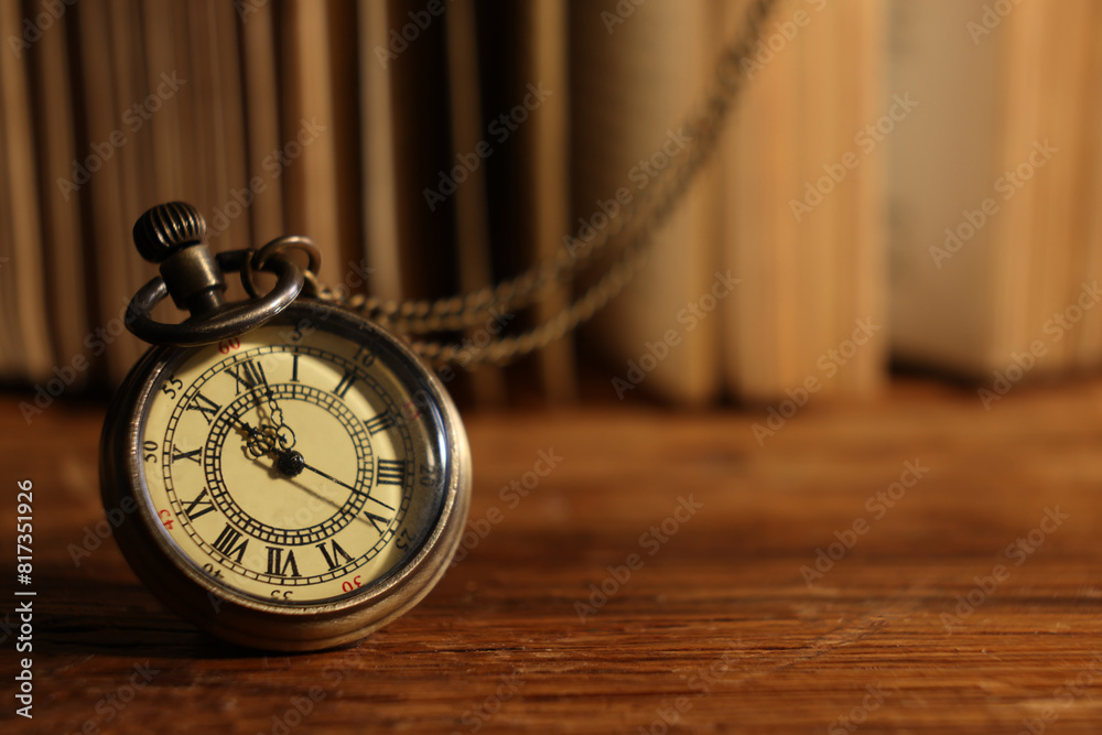Pocket clock with chain on wooden table, closeup. Space for text