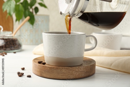 Pouring coffee into cup at white wooden table, closeup
