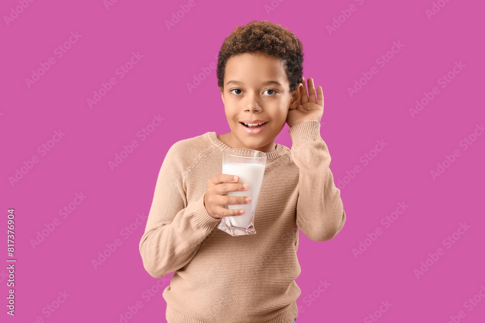 Little African-American boy with glass of milk hearing something on purple background Little African-American boy with glass of milk hearing something on purple background