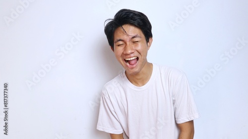 young asian man in white shirt funny expression laughing, happy photo